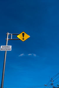 Low angle view of road sign against blue sky