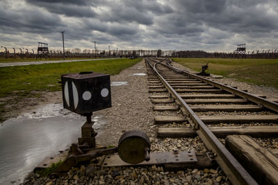 Surface level of railroad track amidst field against sky