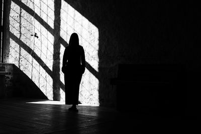 Silhouette woman standing against wall in building