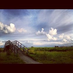 Scenic view of grassy field against cloudy sky