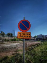 Information sign on road by field against sky