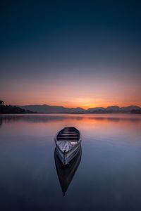 Boat on lake against sky during sunset