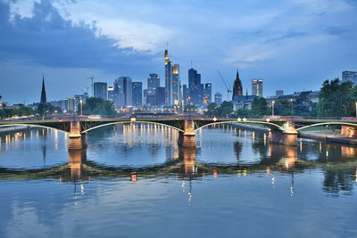 Bridge over river by buildings against sky in city