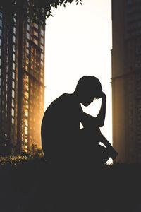 Silhouette of woman sitting at sunset