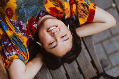 Joyful young woman enjoying peaceful moment lying on bench on park with music