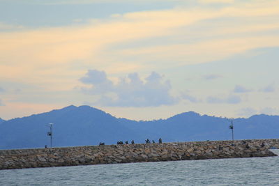 Scenic view of sea by mountains against sky