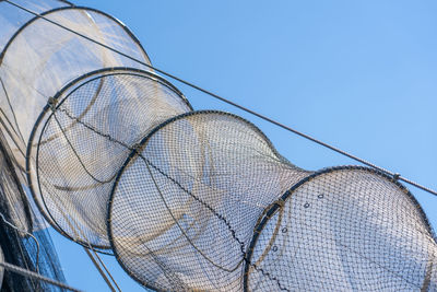 Low angle view of fishing net against clear blue sky