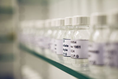 Close-up of bottles with text on shelf at laboratory