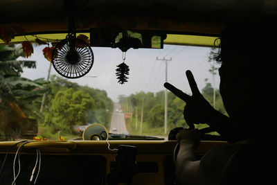 Silhouette man showing peace sign while driving car