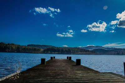 Pier over lake against blue sky