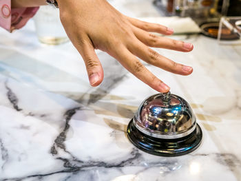 Cropped hand ringing service bell on marble table