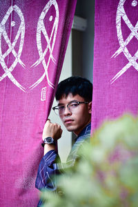 Portrait of young man standing against pink wall