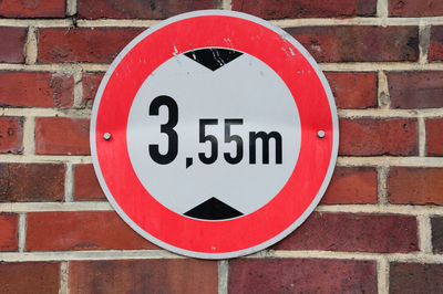 Close-up of road sign on brick wall