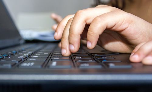 Cropped hands of person using computer