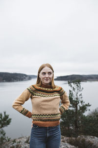 Portrait of young woman standing against sky