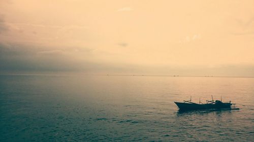 Boats in sea at sunset