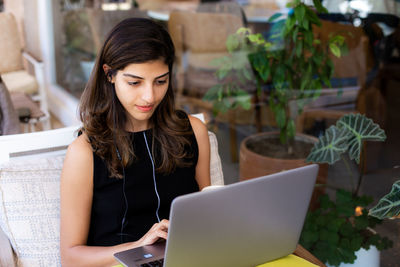 Beautiful young woman working remotely on laptop at outdoor cafe