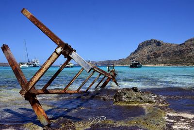 Abandoned ship on beach against clear blue sky