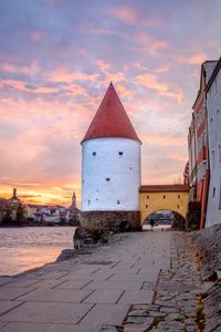 Building by sea against sky during sunset