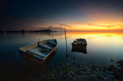 Boat moored on sea against sky during sunset