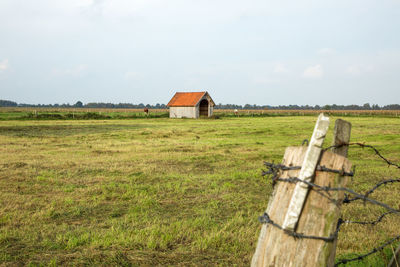 Wooden house on field against sky