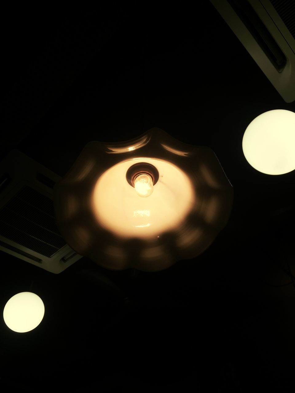 LOW ANGLE VIEW OF ILLUMINATED ELECTRIC LIGHT BULB AGAINST BLACK BACKGROUND