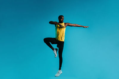 Low angle view of man jumping against blue sky