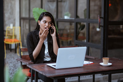 Young woman using laptop while sitting on table