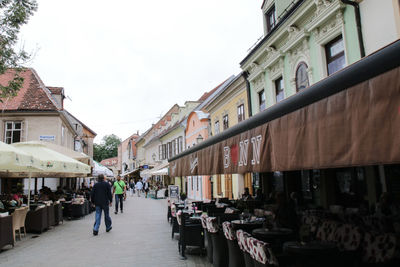 People walking on street amidst buildings in city