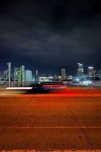 Illuminated buildings by city against sky at night