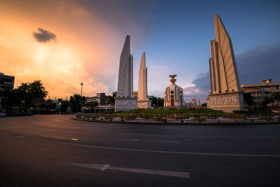 View of city street and buildings against sky during sunset