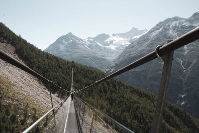 Metal footbridge for hikers that crosses the valley between two mountains