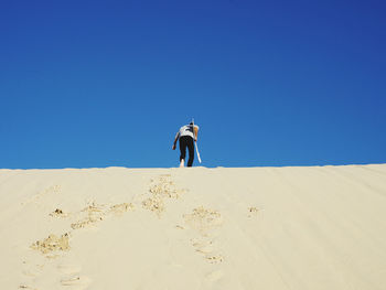 Full length of man on sand dune against clear sky