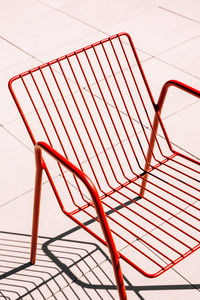 Summer outdoor red metal chair placed on white floor in sunlight with shadow