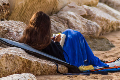 Rear view of woman sitting on beach