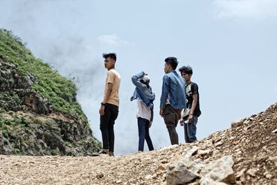 Low angle view of friends standing against sky