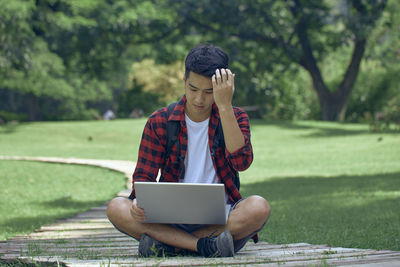 Man using mobile phone while sitting on grass