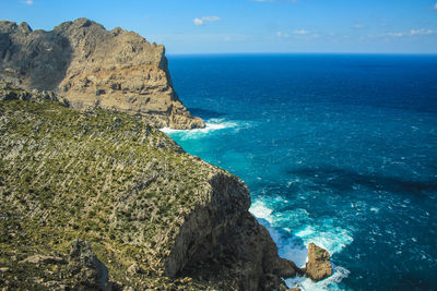 Rock formations by sea against blue sky