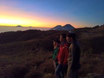 Man standing on mountain against sky during sunset