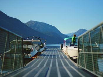 Boats moored by pier on lake against mountains and sky