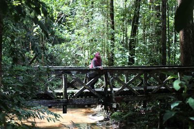 Man standing on footbridge in forest