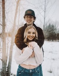 Portrait of smiling young woman standing in snow