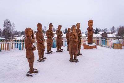 People standing on snow covered landscape against clear sky