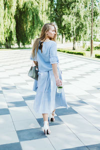 Fashion pretty cool young girl with shopping bags walking on a city street. young blonde woman 