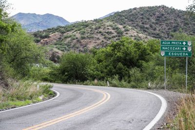 Road leading towards mountains against clear sky