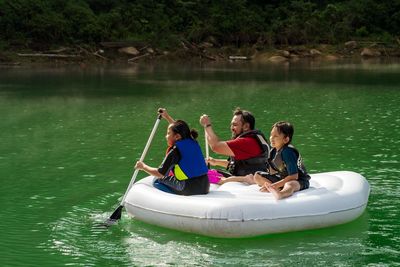 Rear view of people sitting on boat in lake