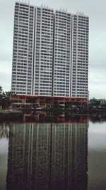 Building by river against sky in city