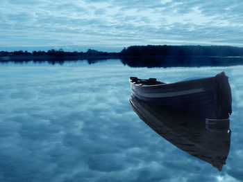 Boat moored on lake against sky