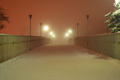 Illuminated road against sky during winter