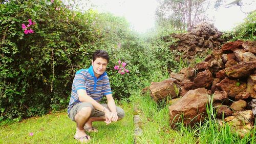 Portrait of smiling mid adult man crouching on grassy field at park